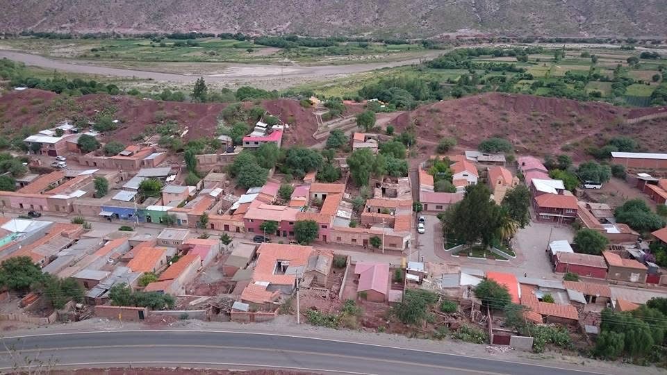 Vista elevada de un pueblo con una plaza y un río al fondo.