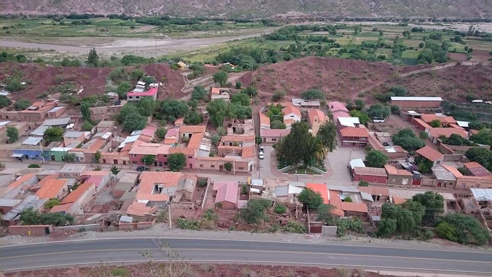 Vista elevada de casas, una plaza y cerros en un valle.